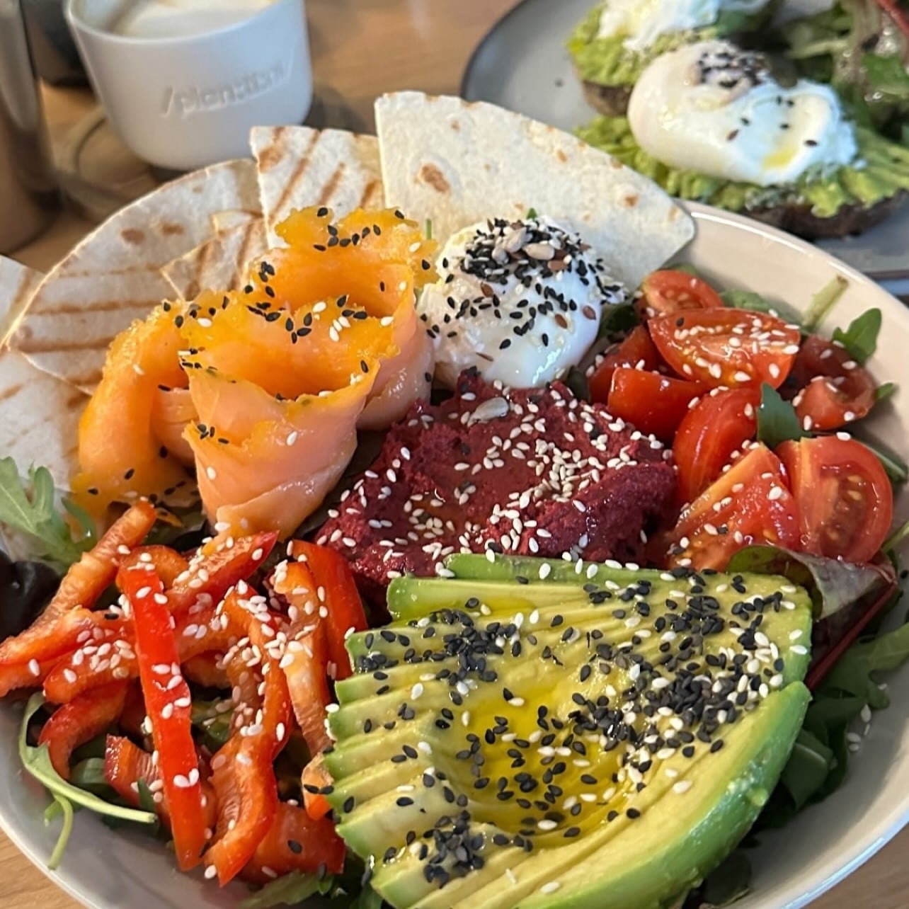 close up cu o salata cu avocado, somon, buratta, ardei, rosii si branza, cu seminte de susan, de la Plantini București