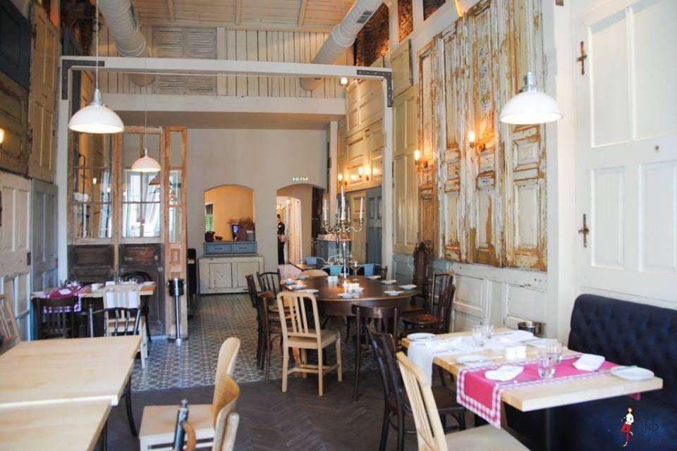interiorul restaurantului Aubergine, unul din retsaurante vegetariene București, cu pereti decorati cu obloane albe patinare, mese cu scuane retro