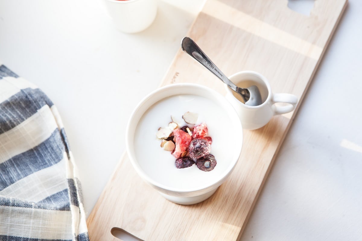 pahar cu iaurt fotografiat de sus, cu fructe si cereale si un bol cu miere langa