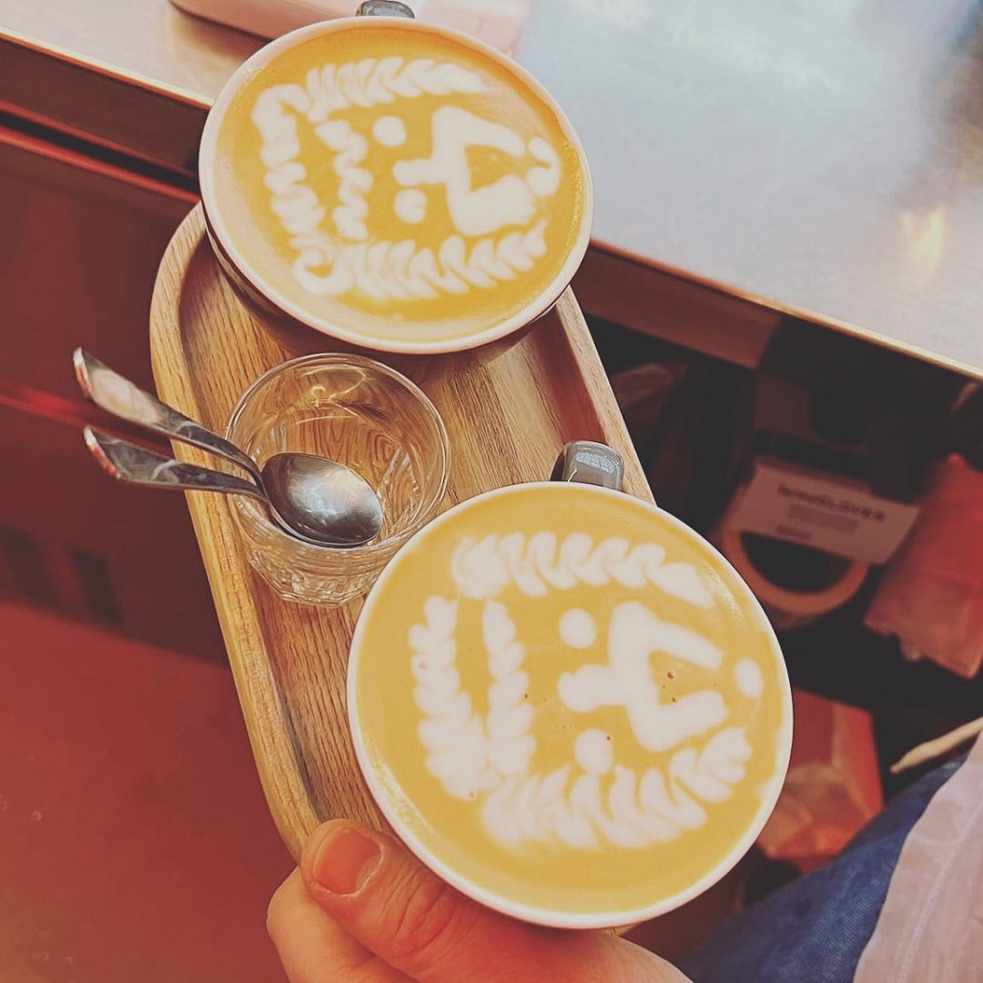 două cești de cafea așezate pe un suport de lemn