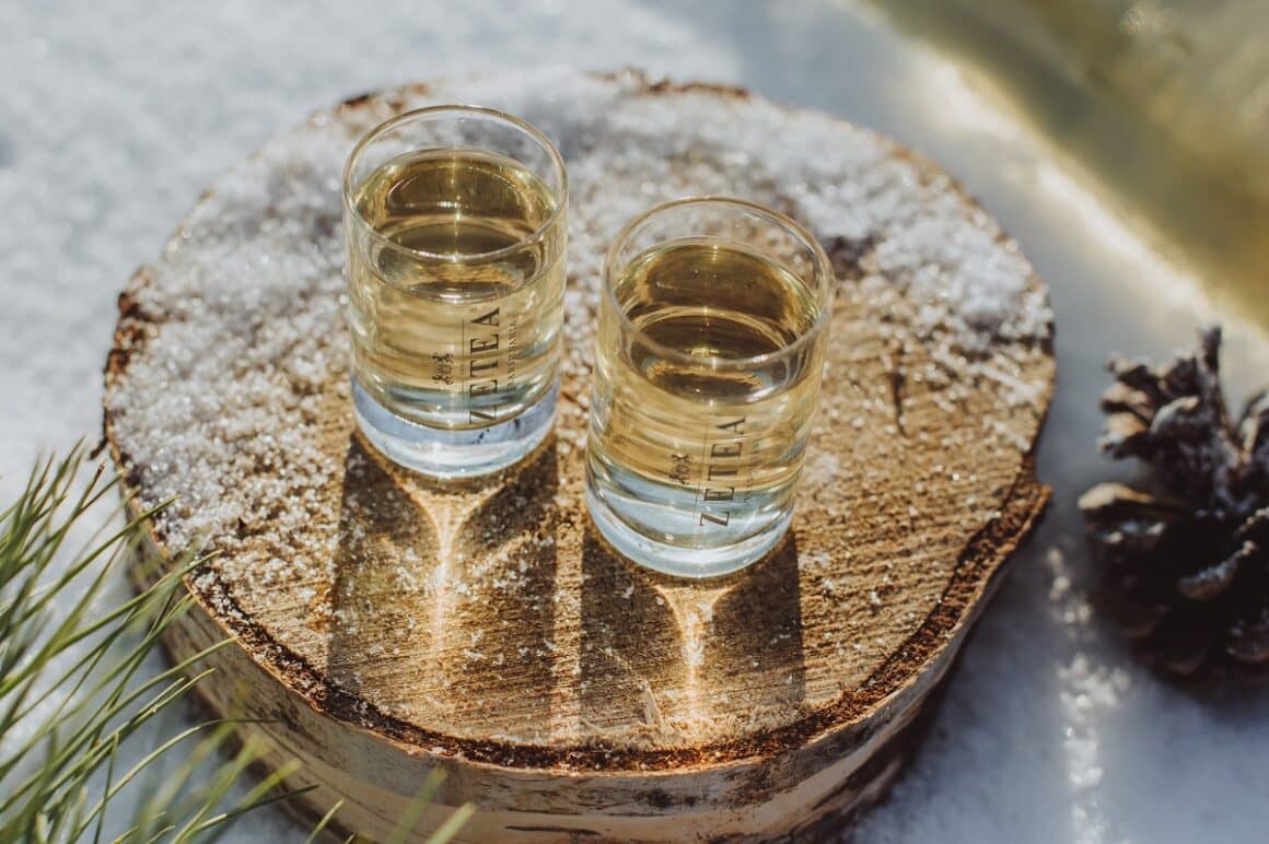 două pahare de shot pline cu țuică Zetea, asezate pe un suport rotund din lemn