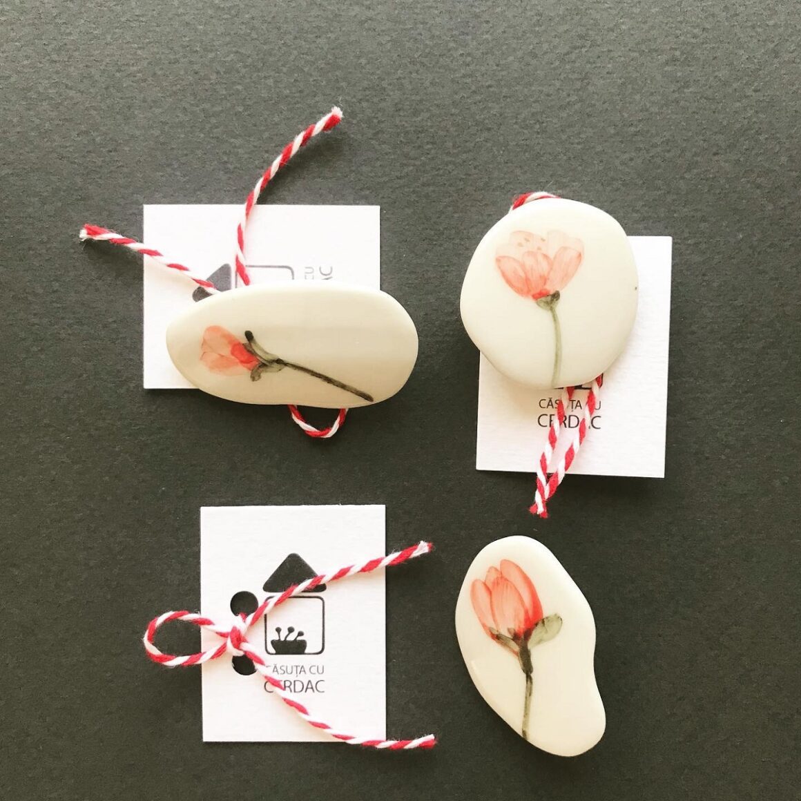 3 martisoare ceramice pictate cu flori, asezate pe fundal negru, la Room 21, unde se ține unul din târguri de Mărțișor din București