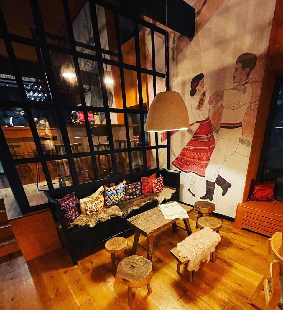 canapea in fata unui perete picatat cu un barbat si o femeie in costume populare, care danseaza