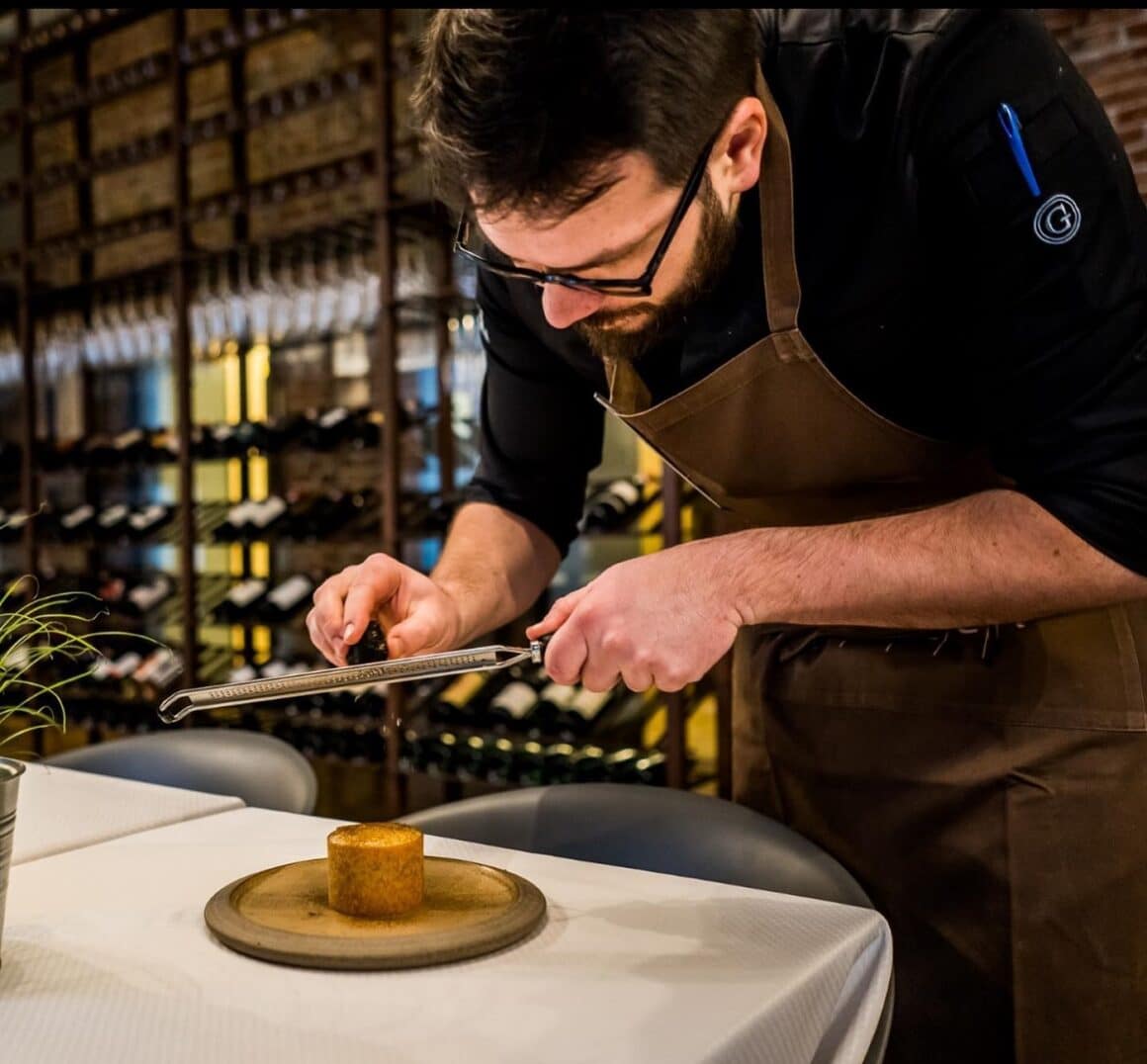 Bucatar razuieste un ingredient deasupra unui preparat de fine dining la restaurant Bracca CLuj, unul din restaurante destinație din țară