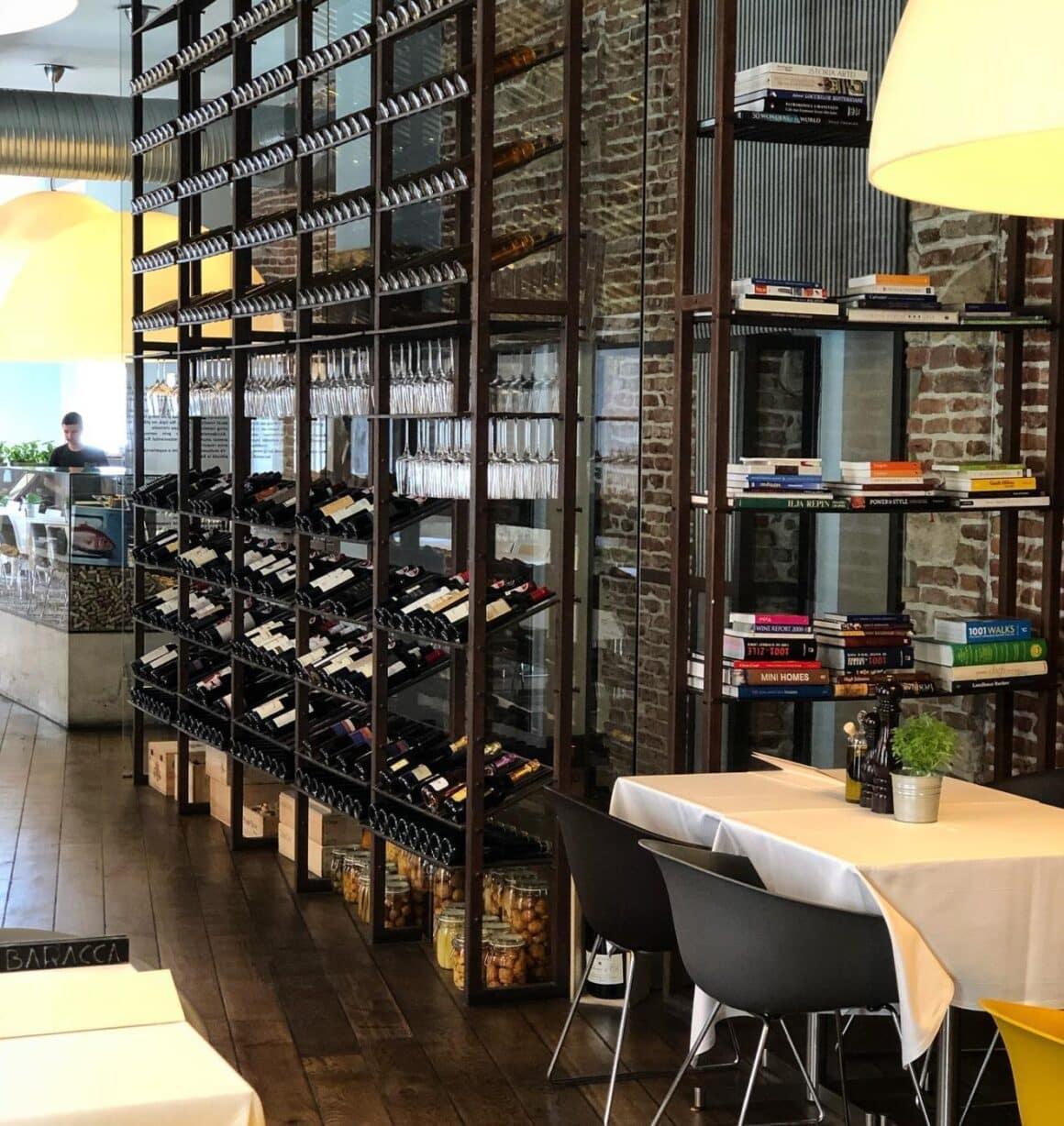 masa de 2 persoane si rafturi cu sticle de vin care acopera un perete la restaurant Baracca