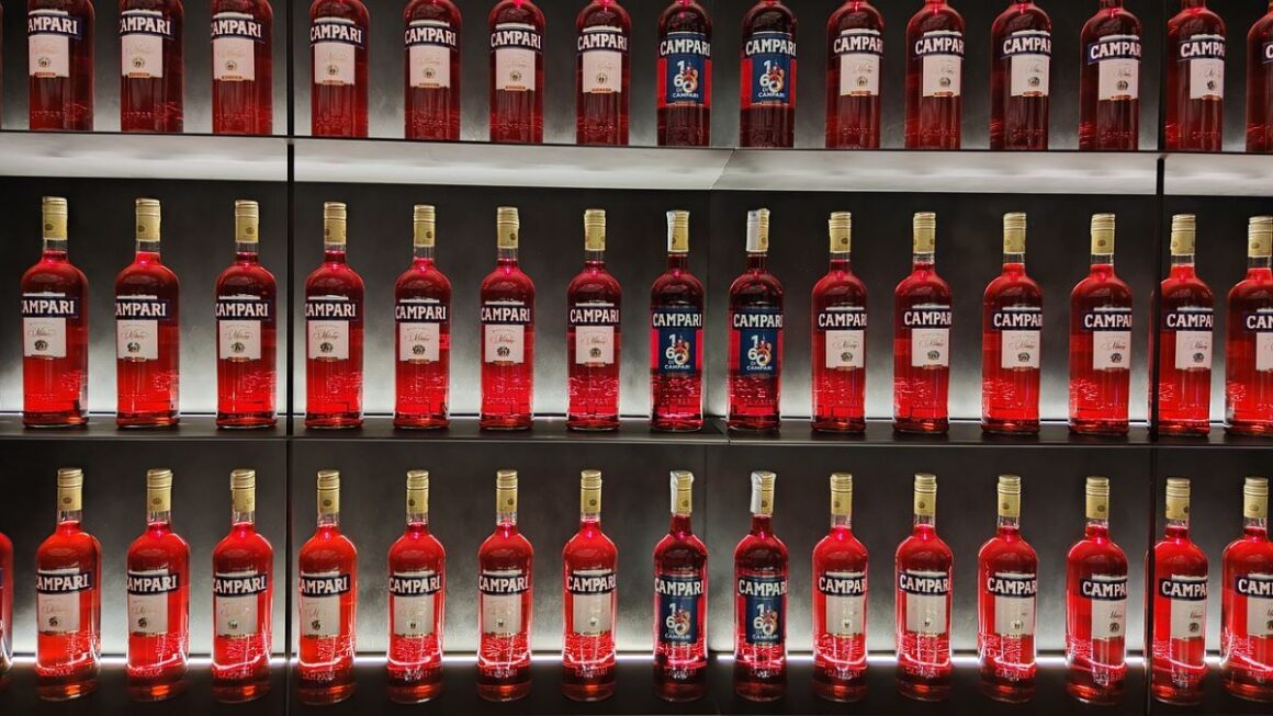 un perete dintr-un bar pe care sunt dispuse mai multe sticle de bitter Campari