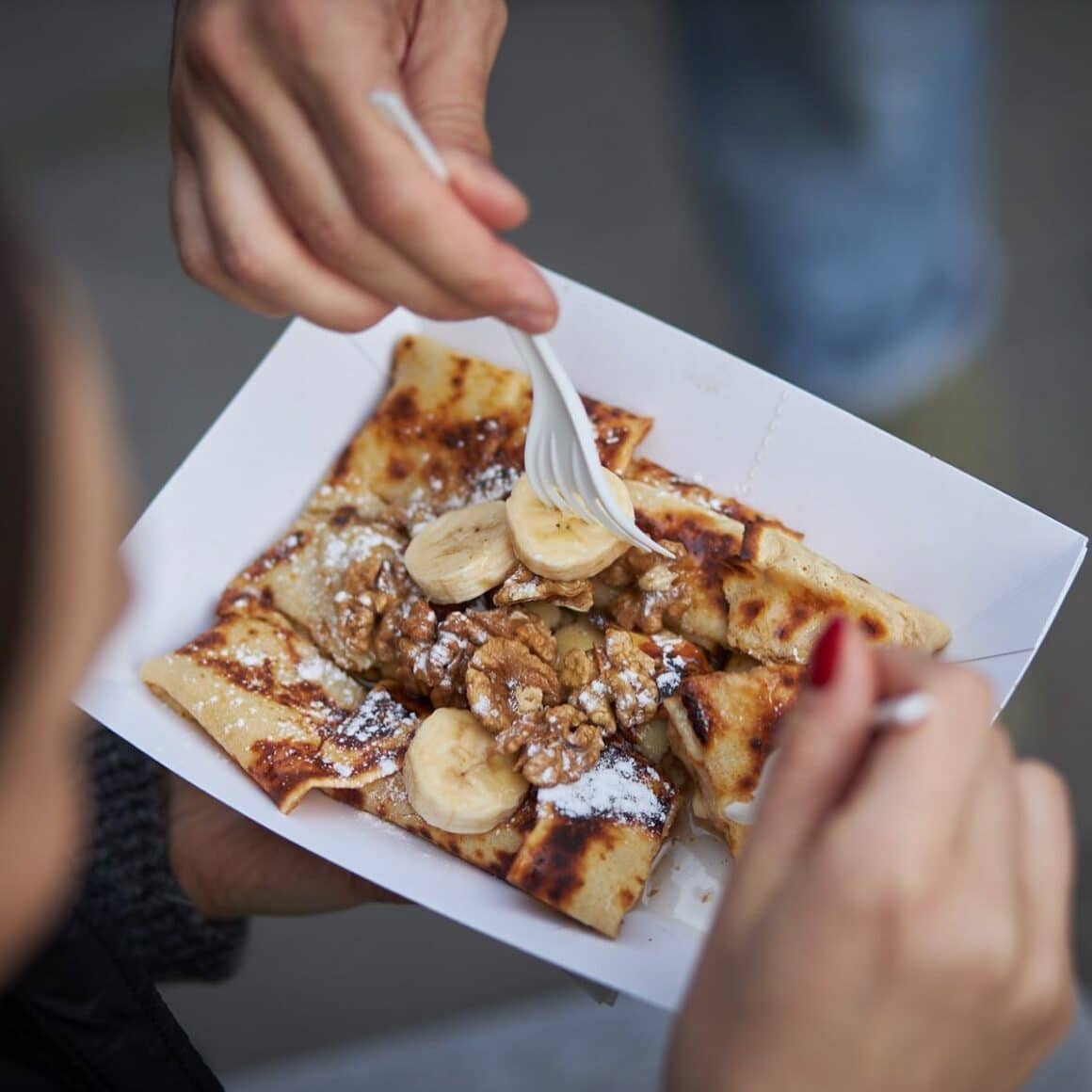 clatite cu ciocolata si banane, in cutie de carton din care cineva mananca cu furculita, la Clăteatarie, loc unde mâncăm clătite bune în București