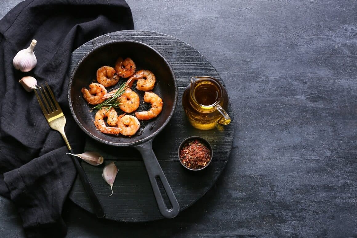 creveti la tigaie, fotografiata de sus, pe fundal negru - cum se prepară fructele de mare