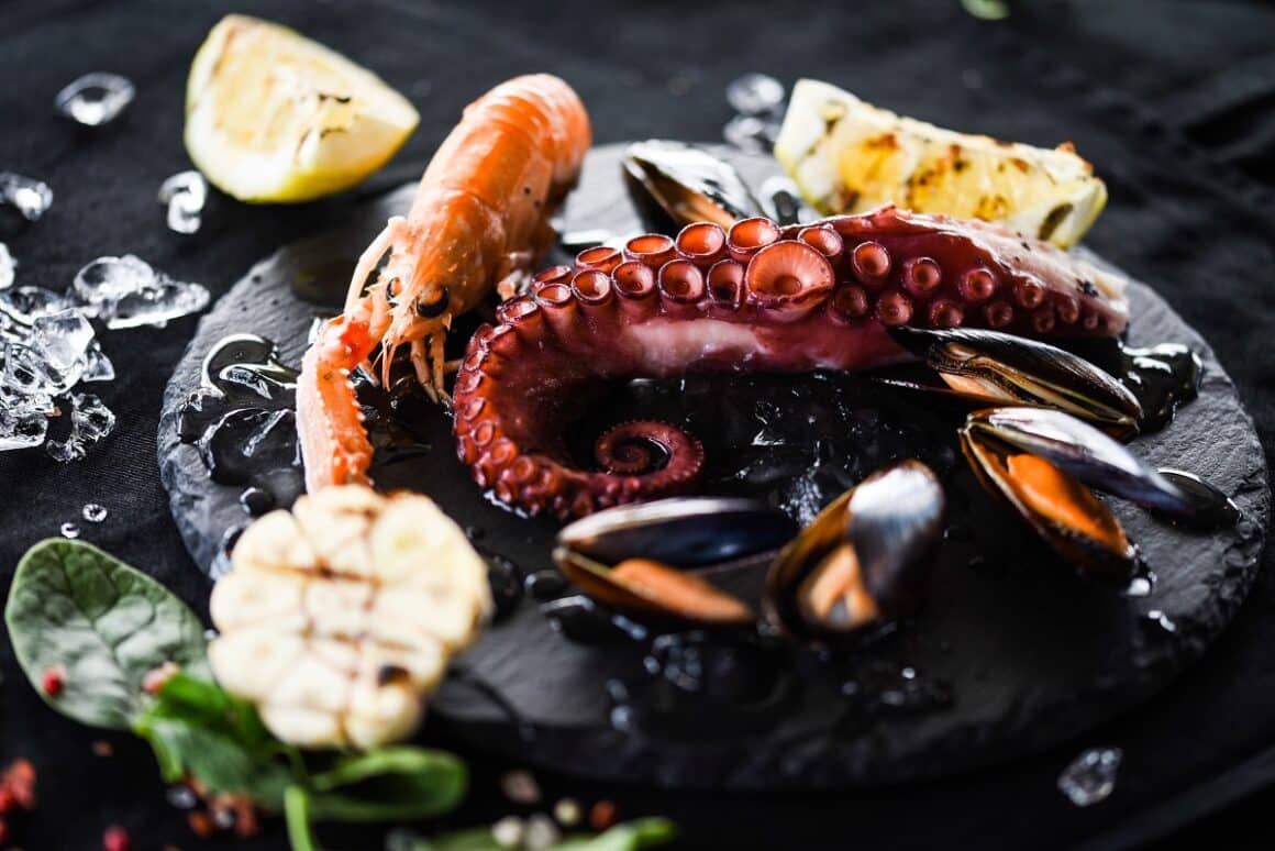 cum se prepară fructele de mare- Platou cu creveti, caracatita si scoici, pe fundal negru