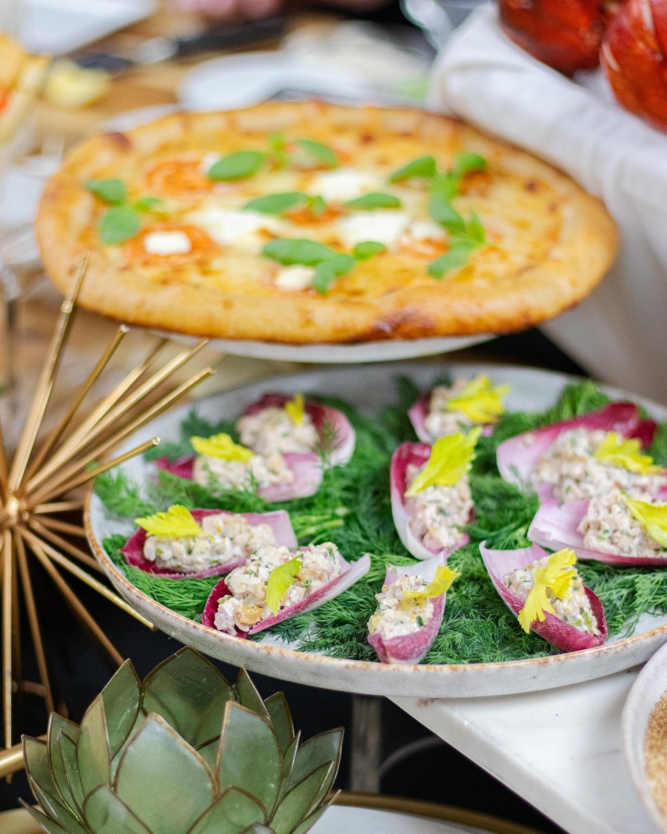 platou cu aperitive si in fundal o pizza blurrata - preparate din meniul de Oscar 2023