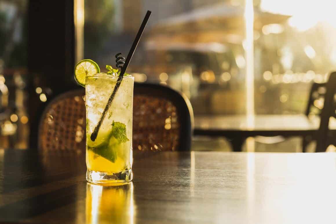 pahar cu cocktail mojito asezat pe o masa la restaurant, la apus - unul din cocktailuri pentru fete