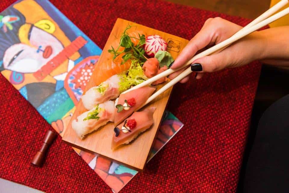 persoana care ia cu betisoare bucati de sushi