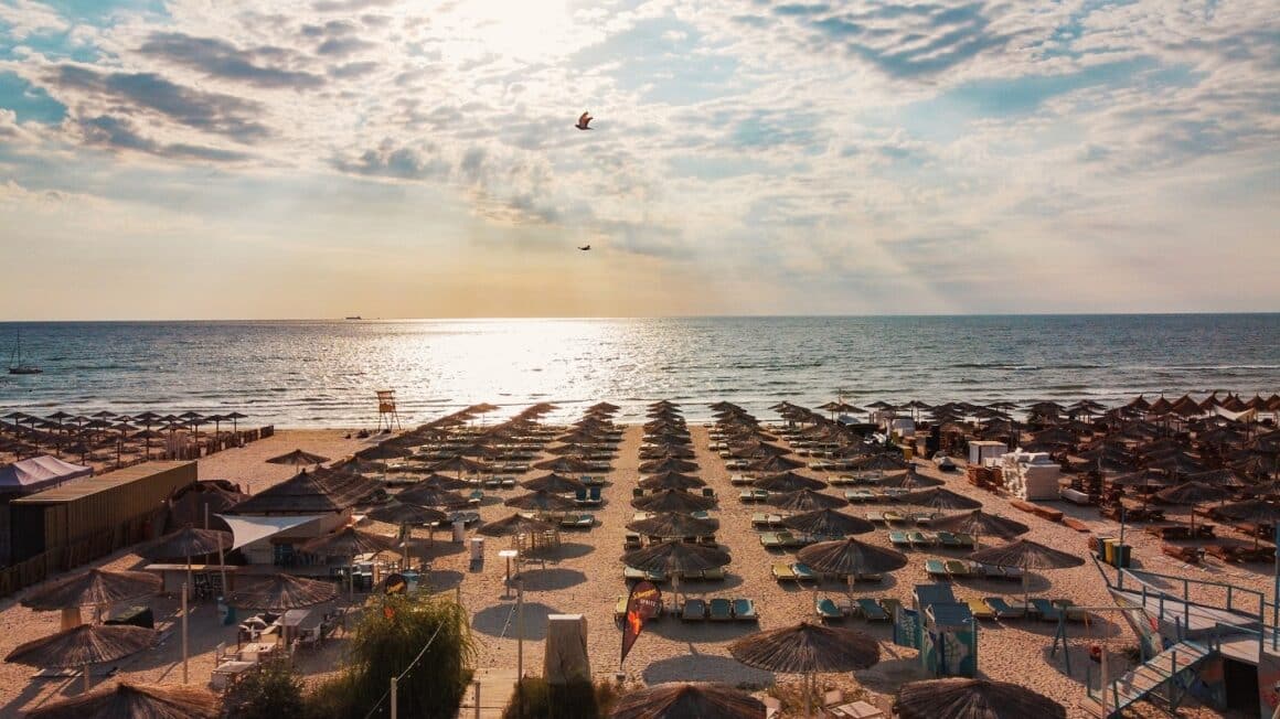 Plaja de la Mamamia plina de sezlonguri si umbrelute, cu marea in fundal. Unde fugim de 1 mai la mare