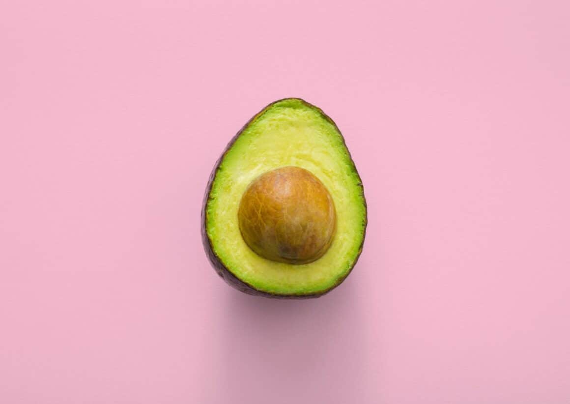 Avocado taiat pe jumatate fotografiat pe fundal mov. Unul din alimente care taie foamea.