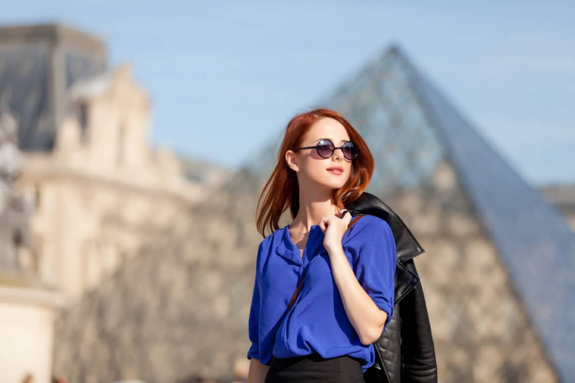 o FEMEIE TANARA CU OCHELARID E SOARE IN FATA MUZEULUI LOUVRE