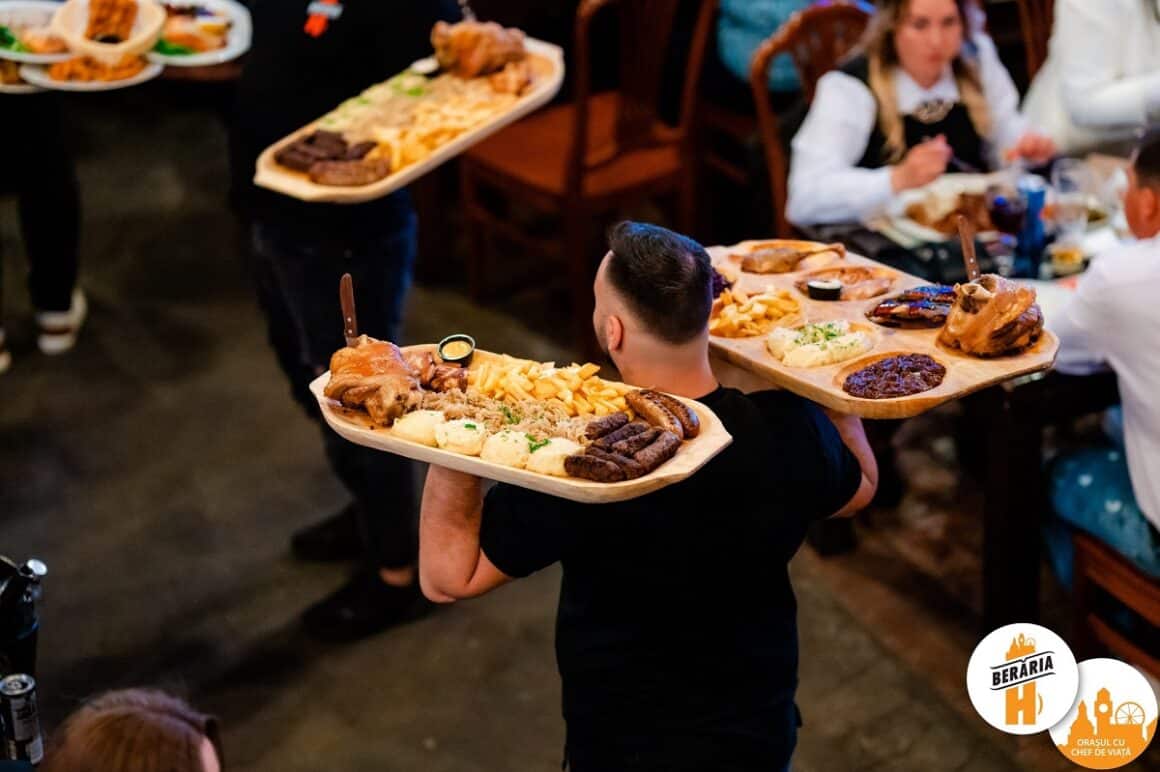 ospatar acre duce platouru cu mici, friptura si carnati la mesele din Beraria H, unde ieșim la restaurant de 1 Mai