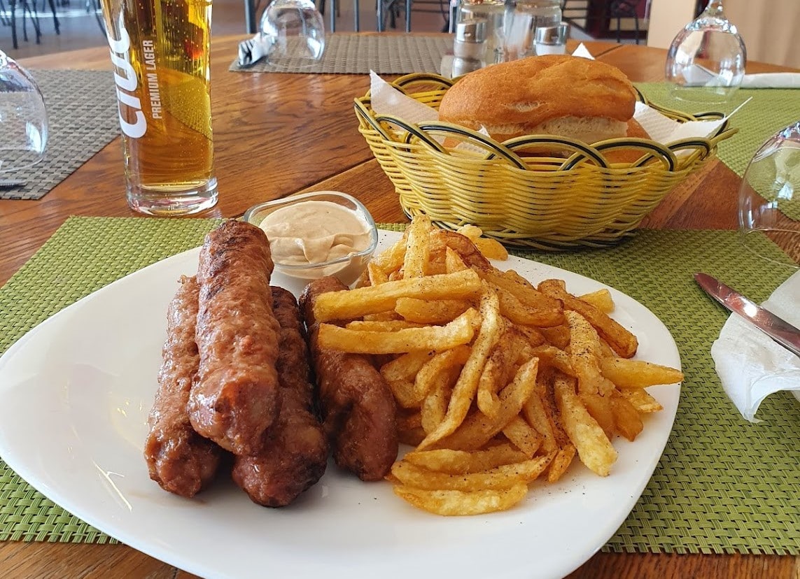 farfurie cu mici si cartofi prajiti, iar in fundal chifle si un pahar cu bere la Gil.