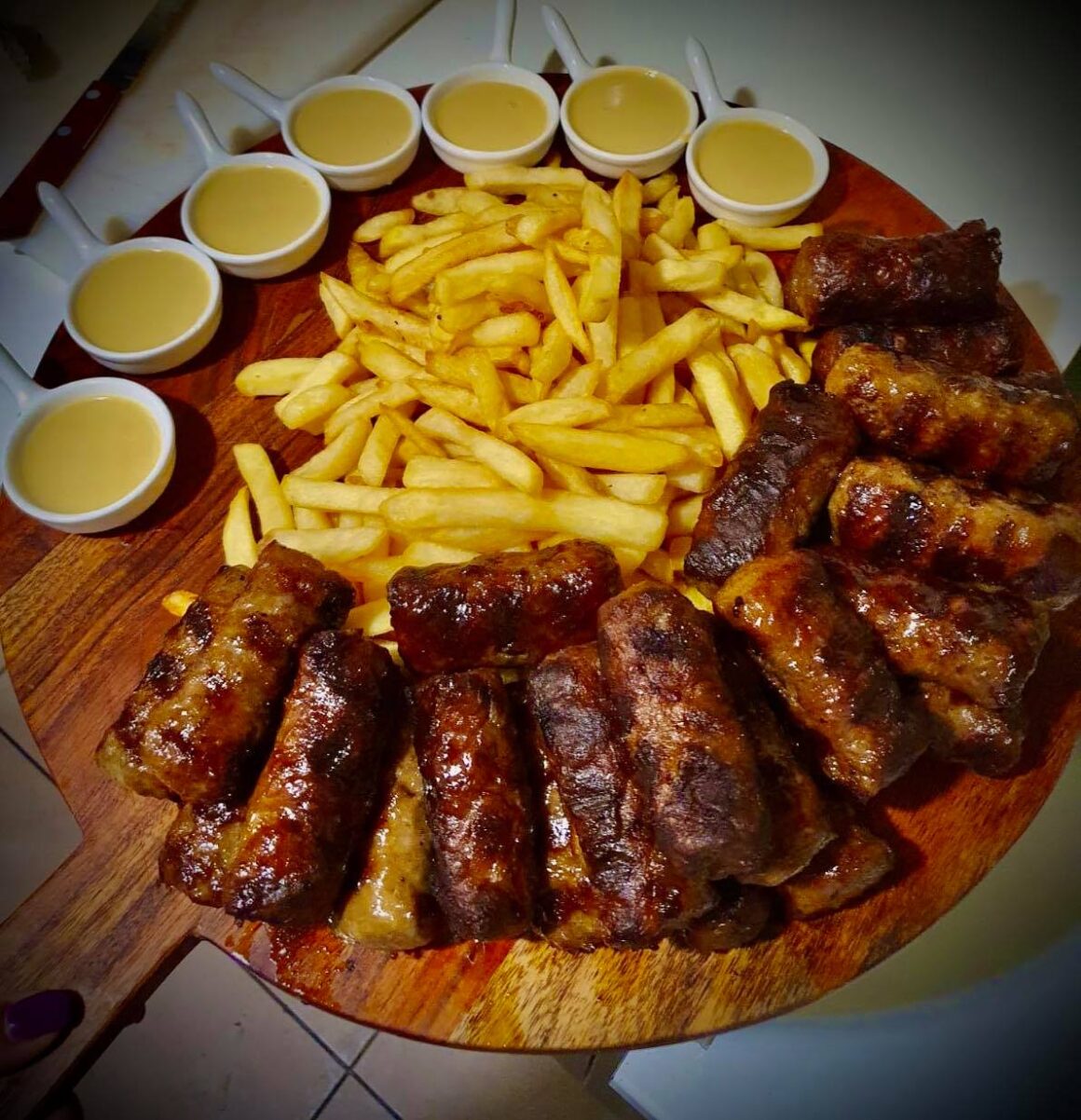 platou mare, rotund, din lemn, cu mici, cartofi prajiti si mustar la Taticu, Sandu Cocosatu. Cei mai buni mici din București