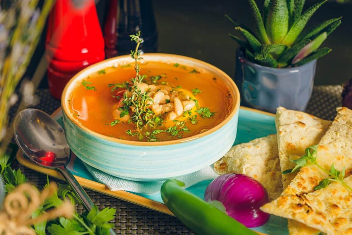 bol albastru cu supa de legume alaturi de focaccia, ceapa si ardei. Preparate de post la Journey Garden
