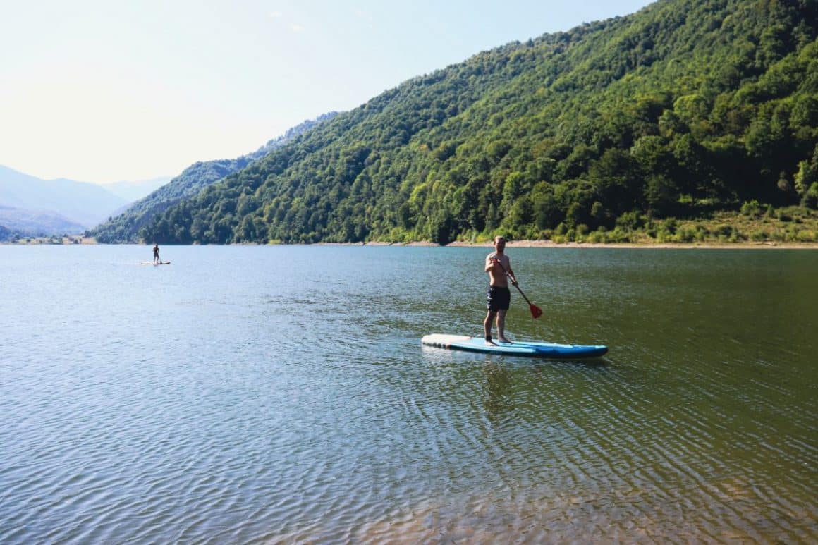 barbat in picioare pe placa, pe lac