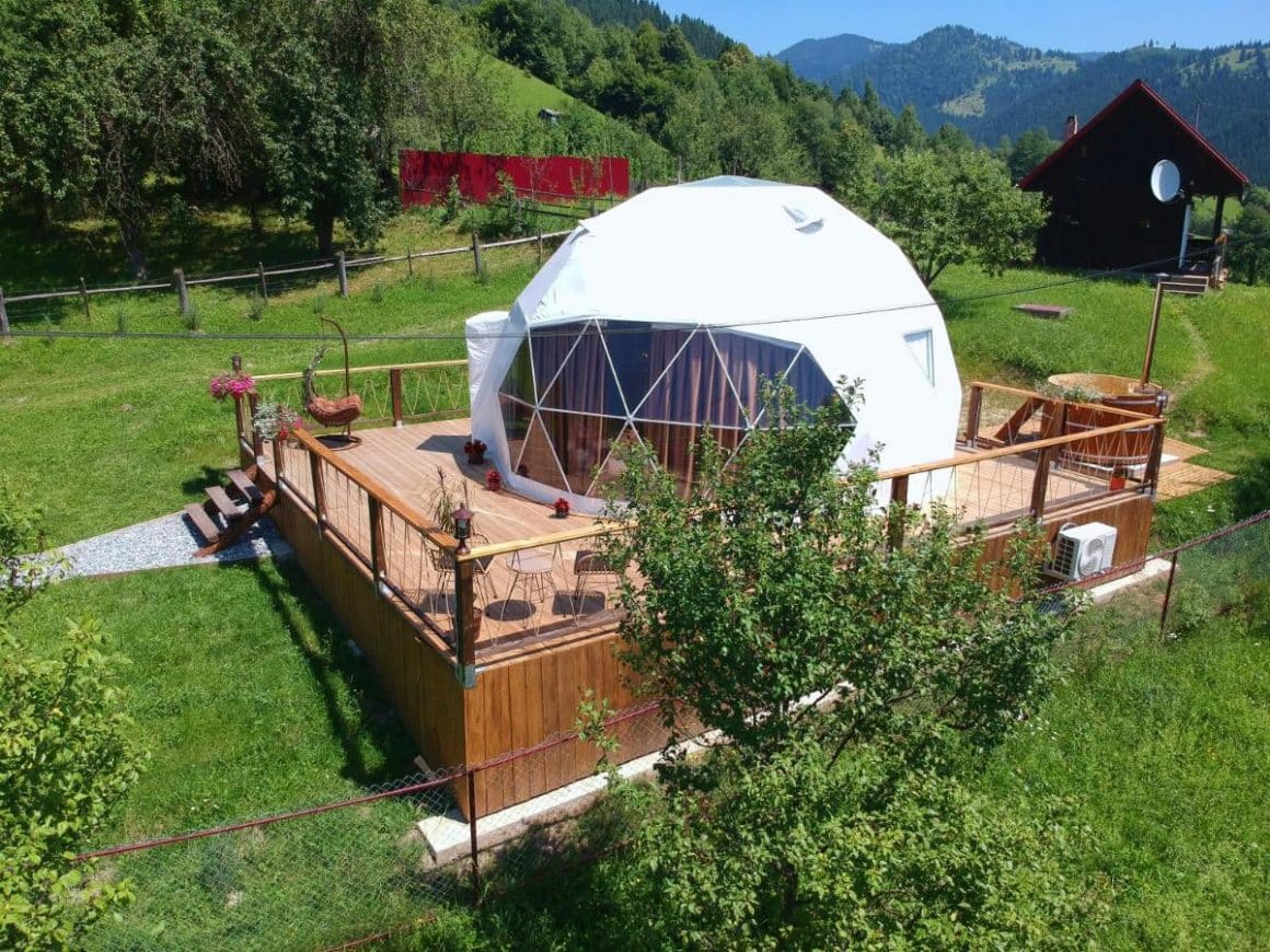 cort de glamping de lux pozitionat pe structura de lemn, in mijlocul unei pajisti la Glamont, Farcașa, Valea Bistriței. Glamping în România