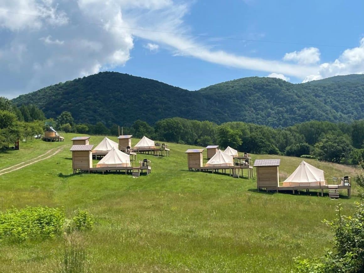 corturi de glamping rasfirate pe o pajiste la munte la The Hundetrs Glamping