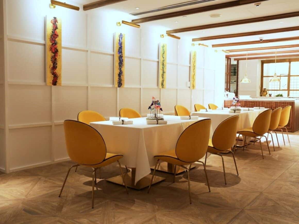 mese patrate cu scaune capitonate galben, si pereti albi la restaurant tresinf dubai