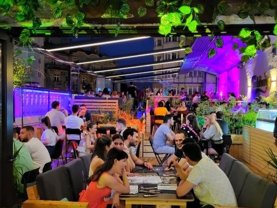 oameni care iau masa pe terasa la Balkon Resto Garden noaptea. Restaurante bune pe Calea Victoriei