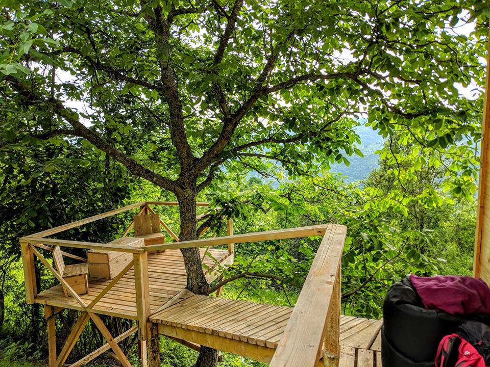 Terasa unei căsuțe în copac, cu platforma de lemn care se intine printre copaci