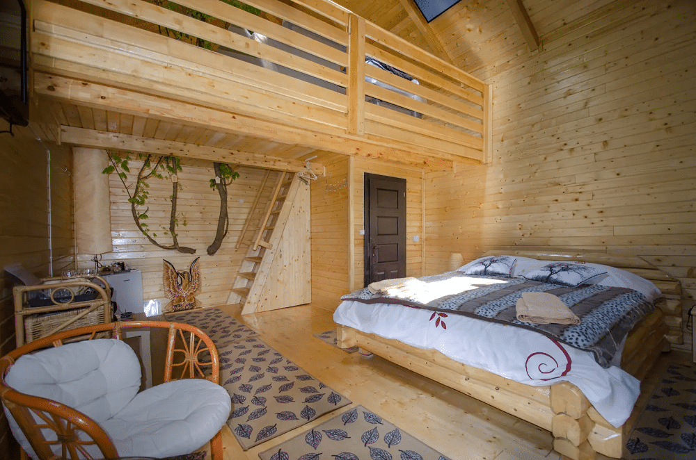 interiorul căsuței în copac de la Cuibul Vulturilor, Maramureș, cu un pat si o masura si interior din lemn