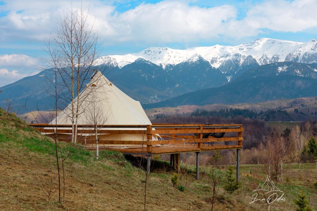 cort de glamping pe platforma de lemn, iar in fundal muntii cu creste acoperiti de zapada, La Odăi, Bran. Glamping în România
