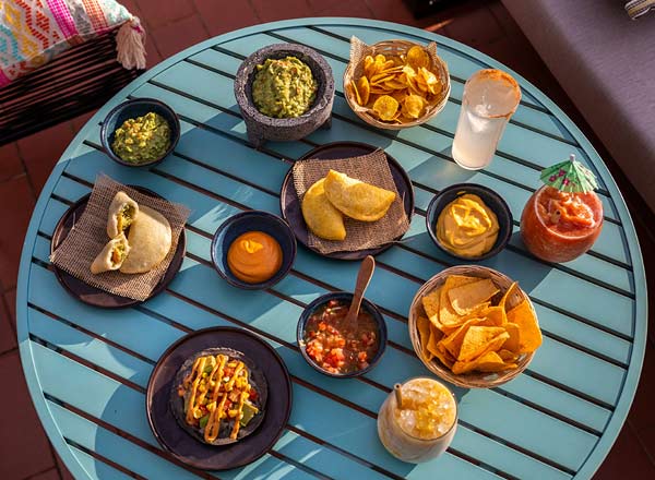 mai multe preparate culinare sunt asezate pe o masa rotunda din lemn, colorata albastru