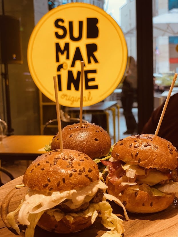 prim plan cu 3 burgeri iar in fundal logoul Submarine Burgers