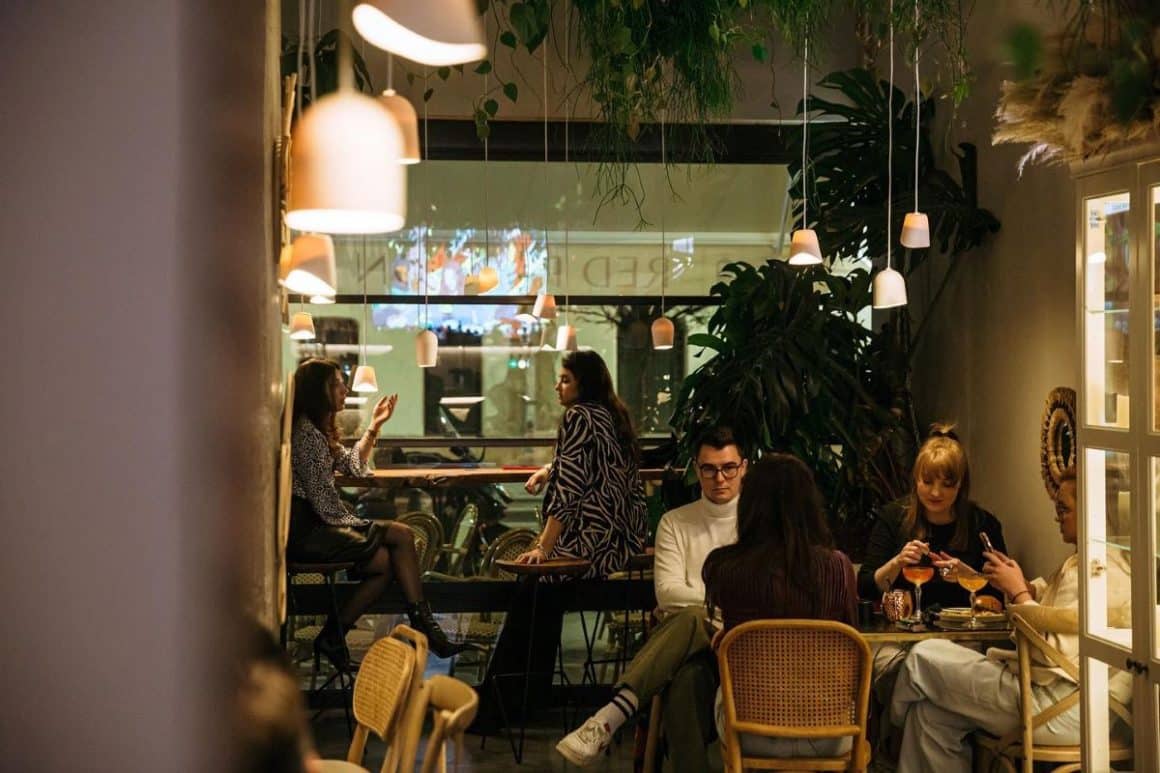 oameni care iau masa seara la interior in restaurantul The Other Saint. Restaurante bune pe Calea Victoriei