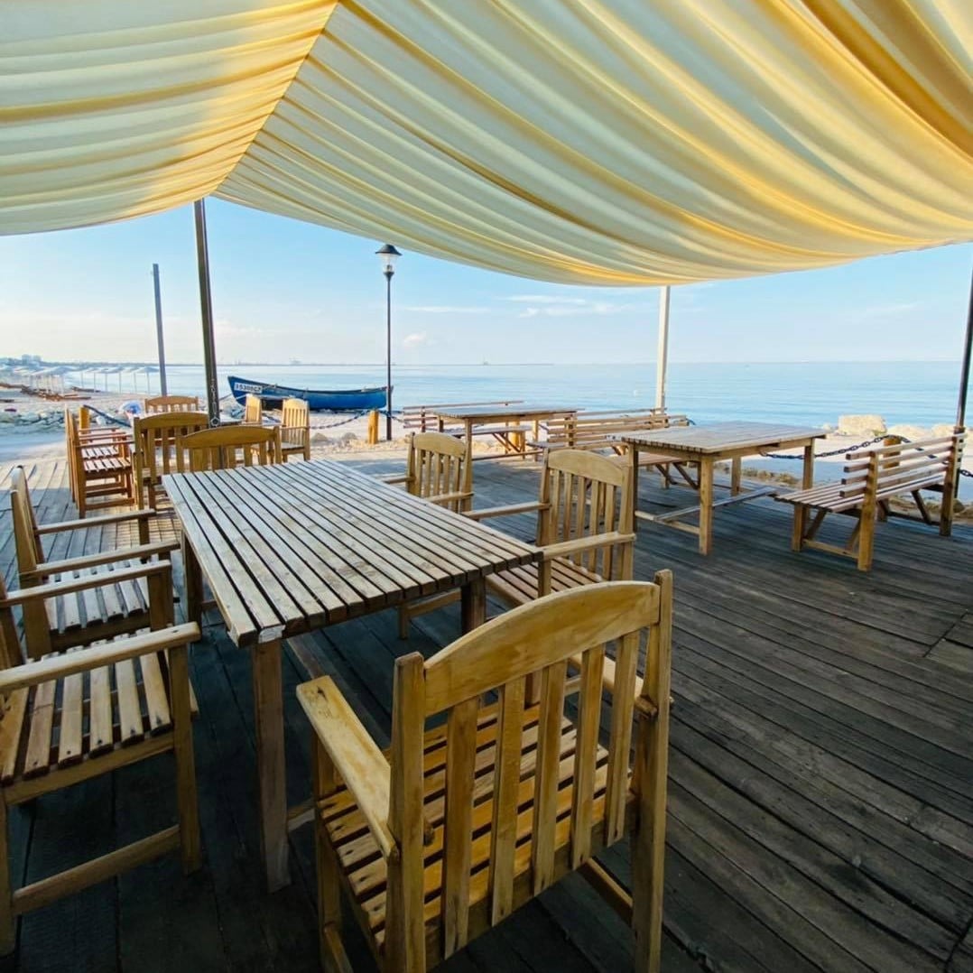 mese pe terasa acoperita de la Poarta Apelor Eforie Sud, cu mare in fundal. Cherhanale de pe litoralul românesc