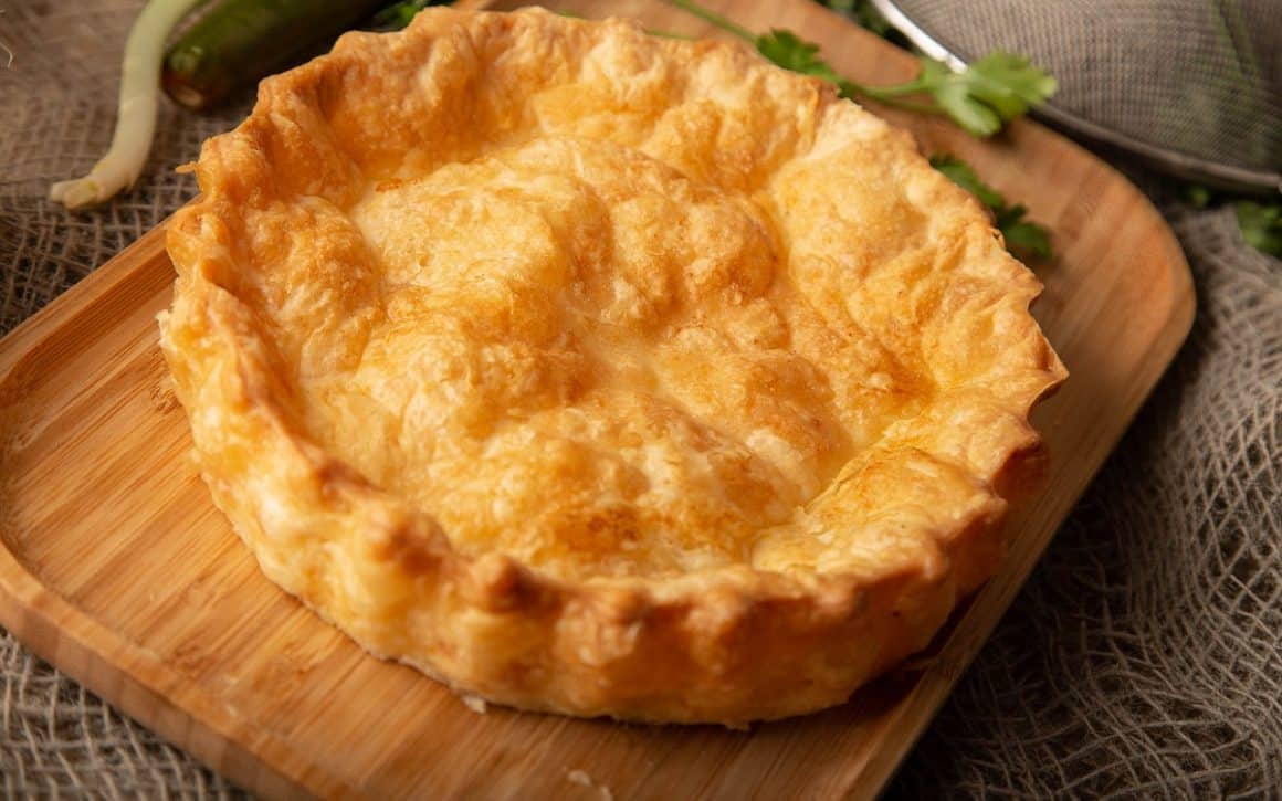 Plăcintă Domnească cu brânză și stafide, fotografiata intreaga, ep un tocator de lemn. Cele mai bune tarte și plăcinte din București. La Plăcinte