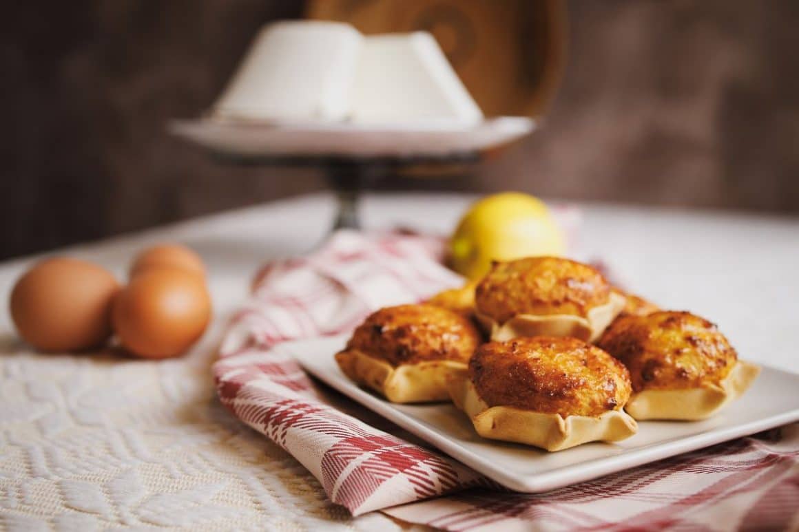 o portie de Pardulas asezata pe o farfurie care este asezata pe un stergar care este asezat pe o masă, alaturi de cateva oua. Preparate tradiționale din Sardinia