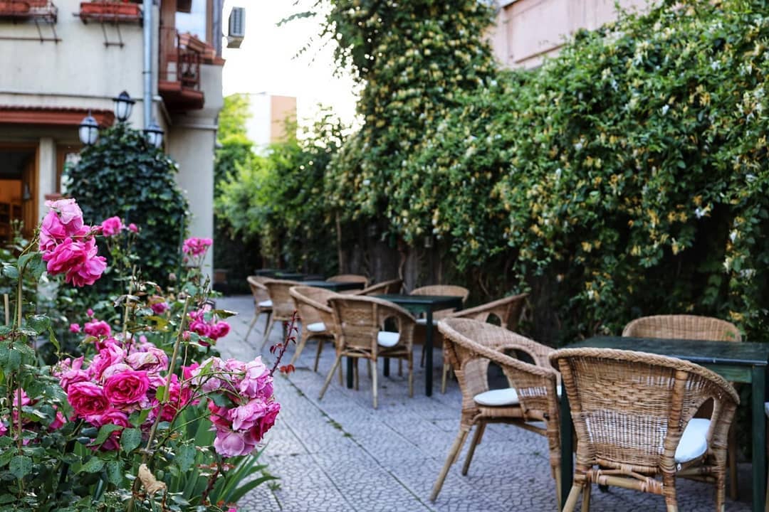 Grădini din Bucurețti: ceainăria Green tea cu mese si scaune din rachita, trandafiri si multa verdeata