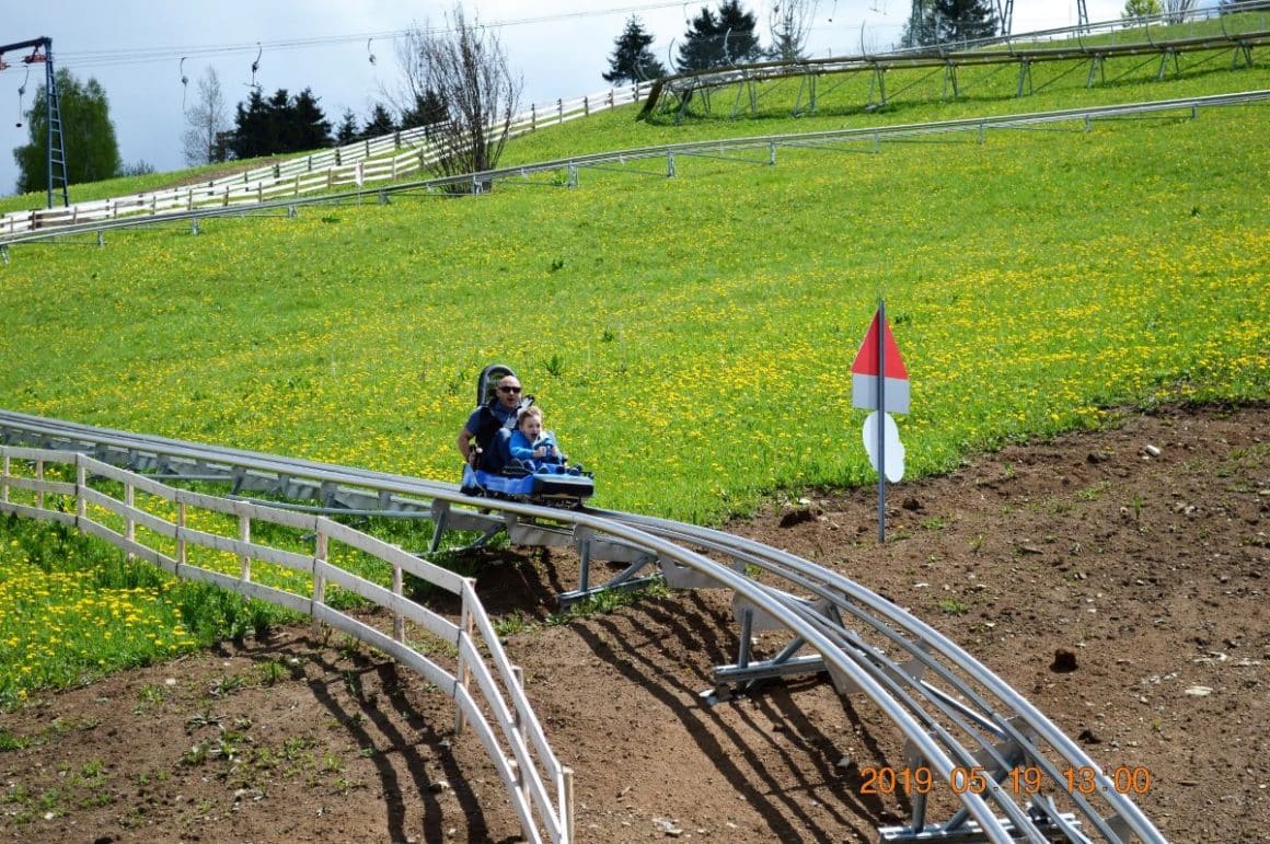 o instalatie de bobpe sine este montata pe un capm verde, iar un copil se da cu bobul pe insralatie