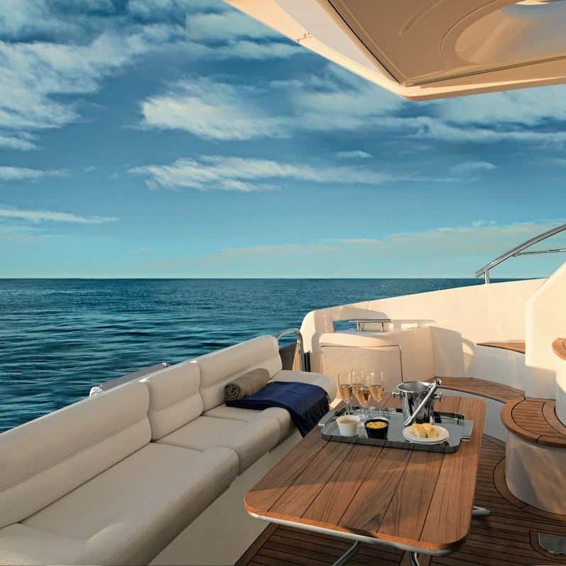 puntea unui iaht cu o masa de lemn și mai multe canapele cu perne albe