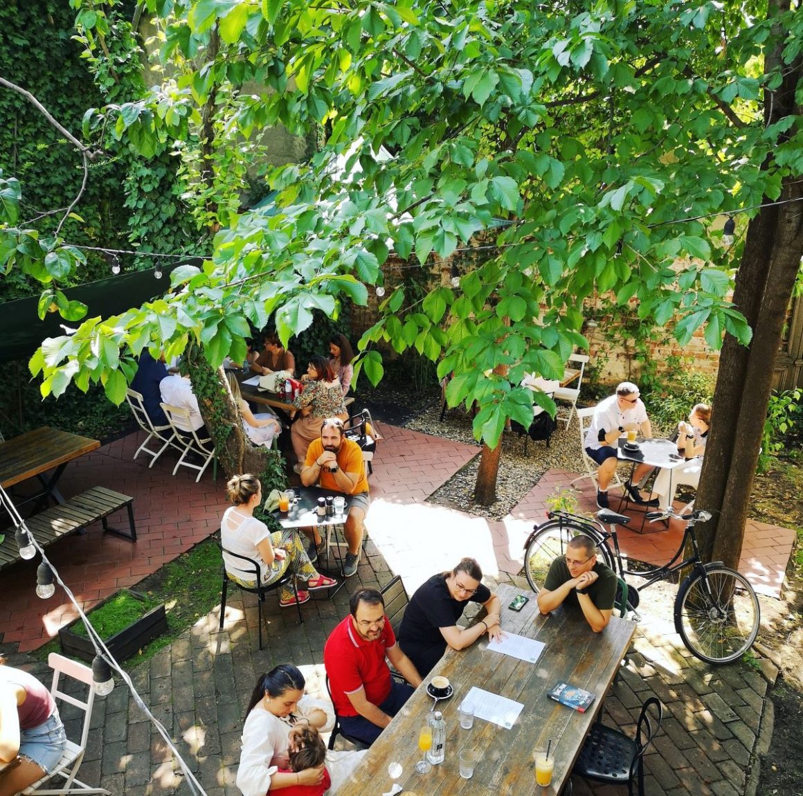 Oameni care iau masa pe terasa a Simbio Bucuresti