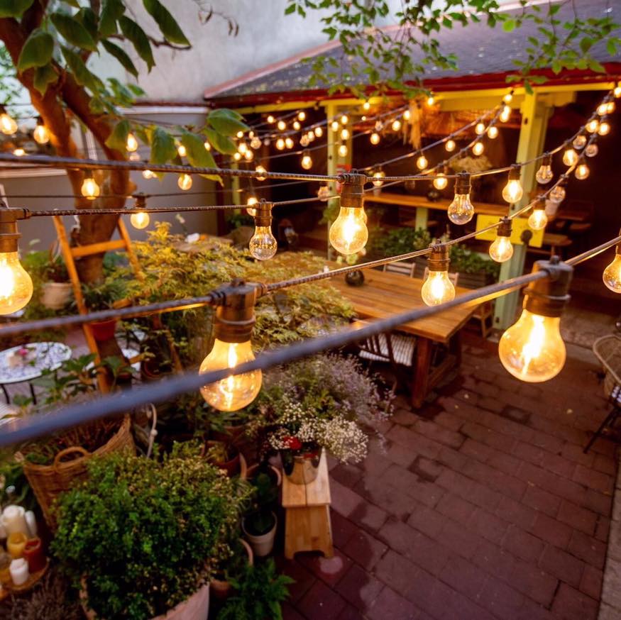 terasa gradinii bacania veche cu multe flori si ghirlande luminoase. Grădini ascunse din București