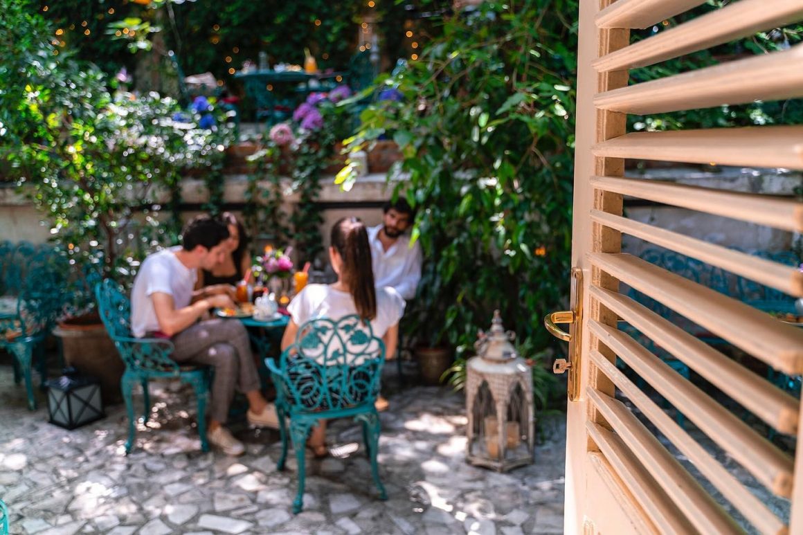 oameni care iau masa in grădina de la ceainăria infinitea 