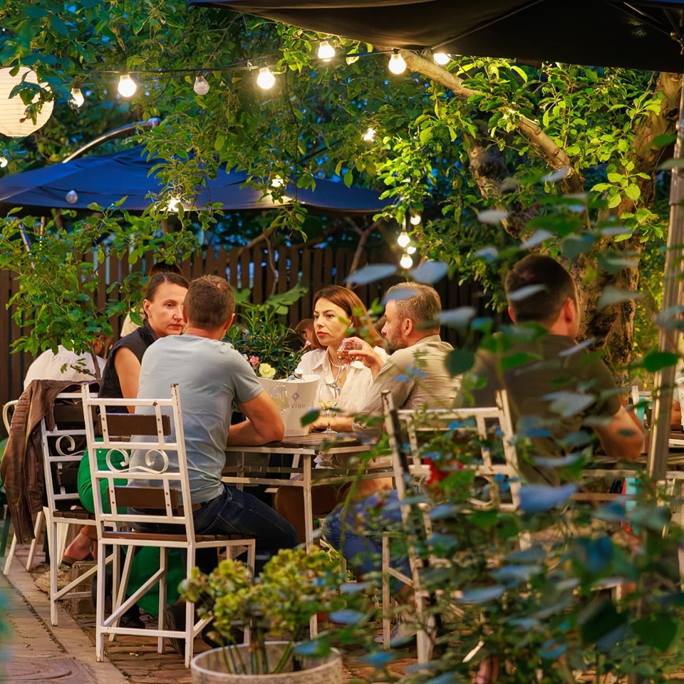 oameni care iau masa in grădina Suento