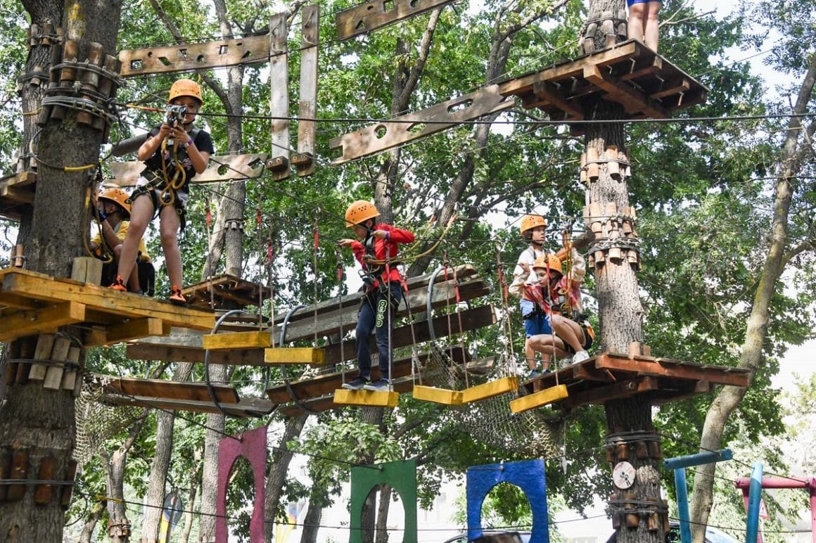 Mai multi copii parcurg un traseu de aventura in copac la Paradis Land Neptun