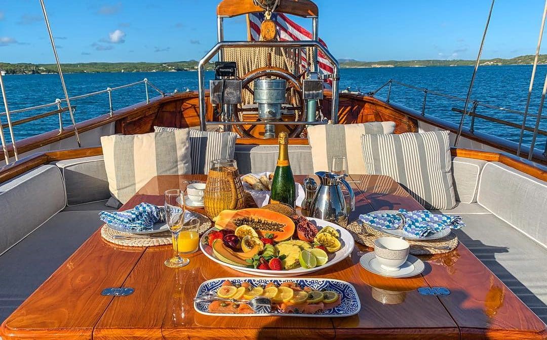 o masă de lemn de pe un iaht este incarcata cu mancare si o sticla de sampanie