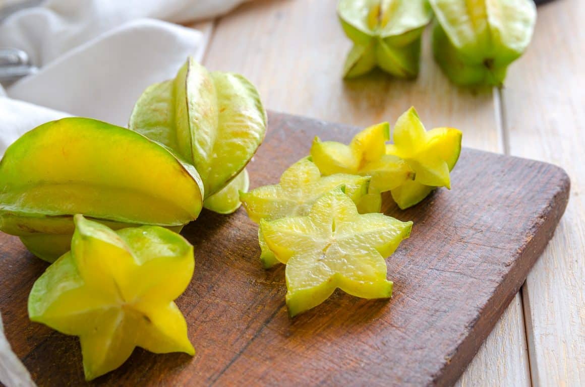Fructe exotice: carambola, sau fructul stea, fotografiat pe tocator de lemn