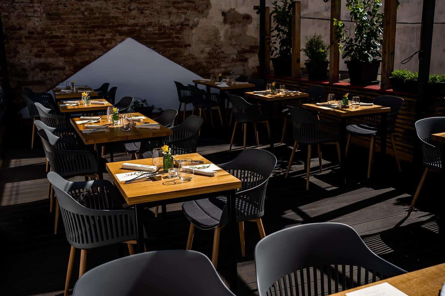 mese de 2 persoane, din lemn, cu scaune inchise la culoare si in fundal un perete de caramida la cimbru author cuisine. Restaurante Cluj