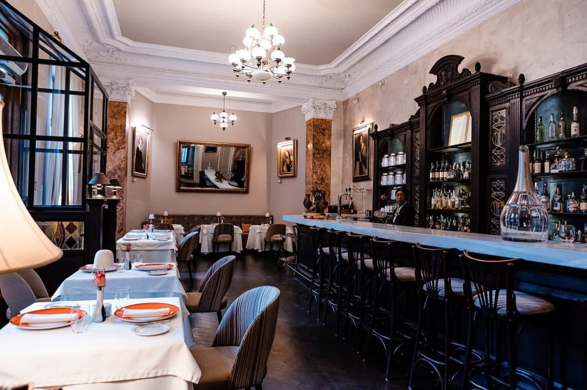 sala de mese de la Relais & Châteaux Le Bistrot Français, cu barul in stanga si mese pe partea dreapta, in partea geamurilor, unul din restaurante franțuzesști din București, decorat in stil clasic