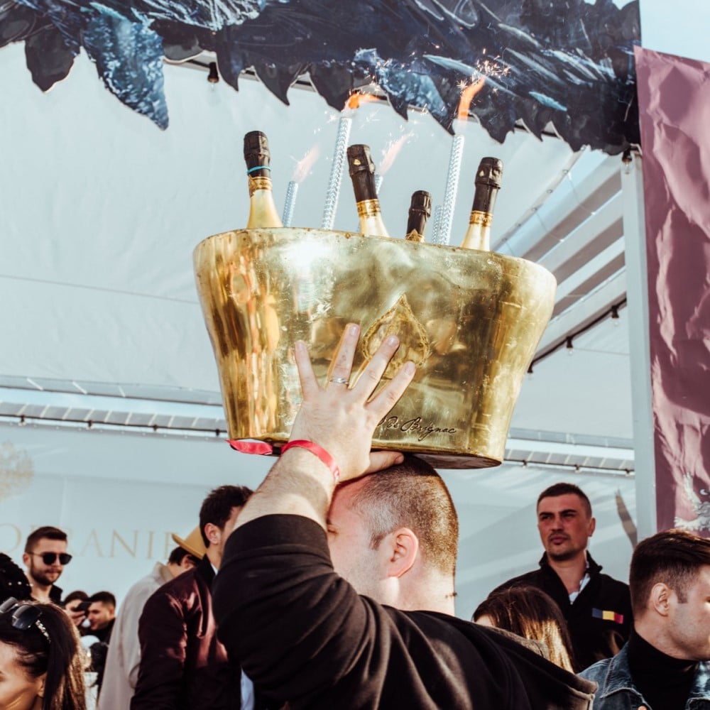 barbat care cara pe cap o frapiera cu mai multe sticle de sampanie